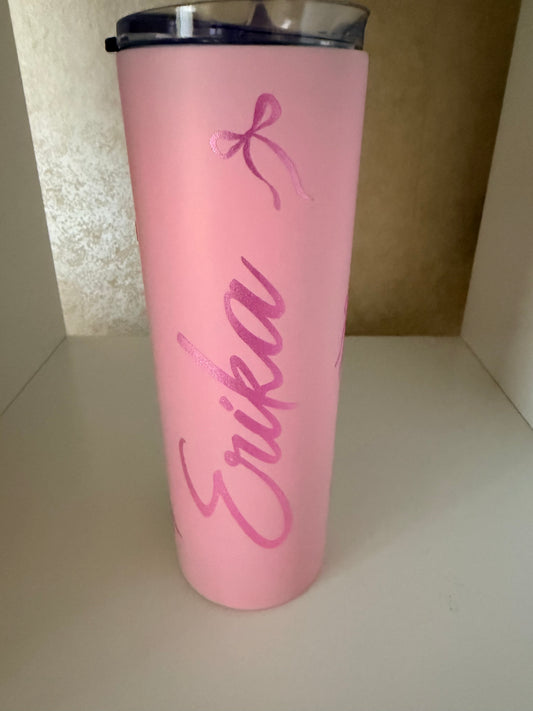 Pink tumbler with 'Ewritten on it against a neutral background